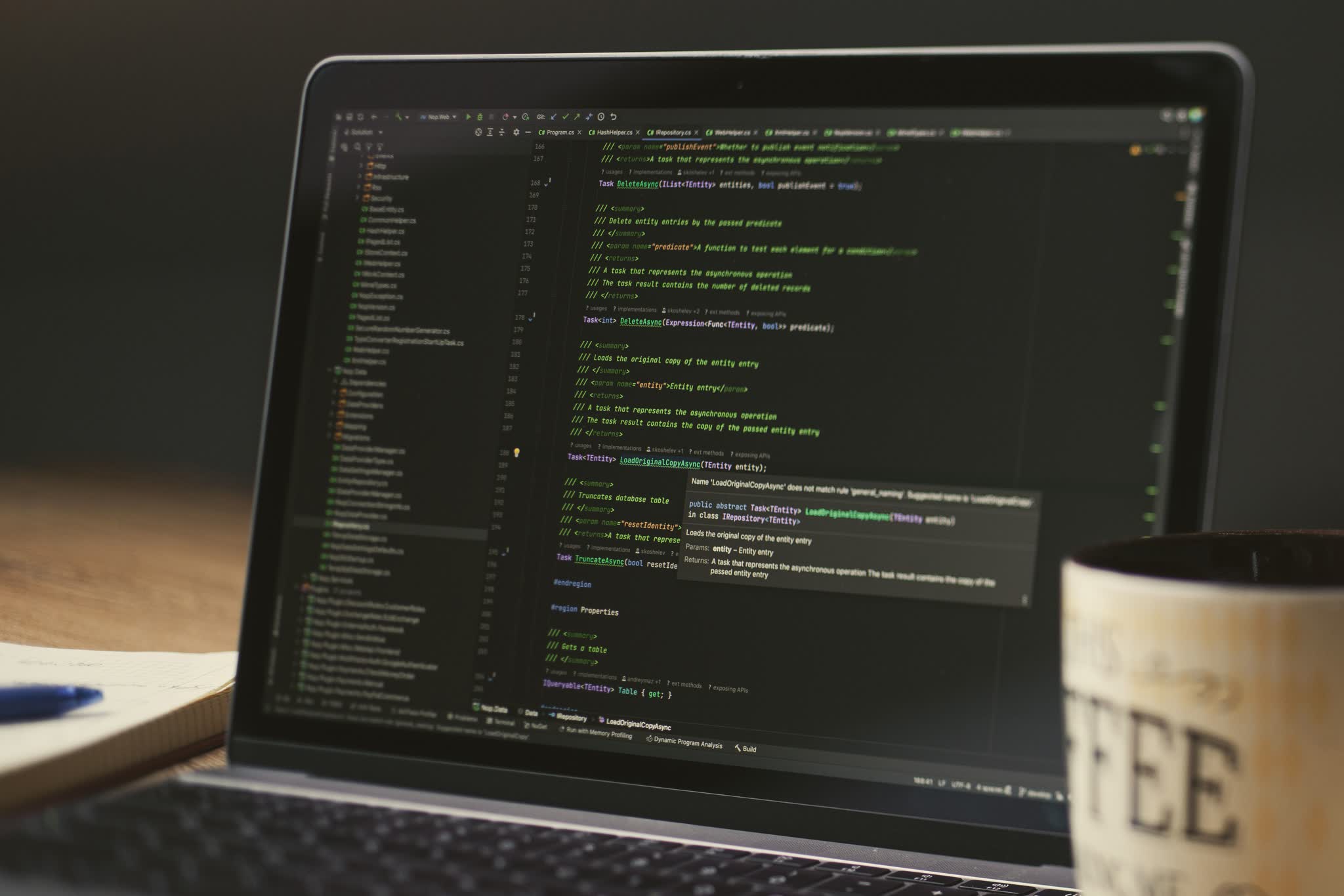A laptop showing an open code editor, beside a cup of coffee.